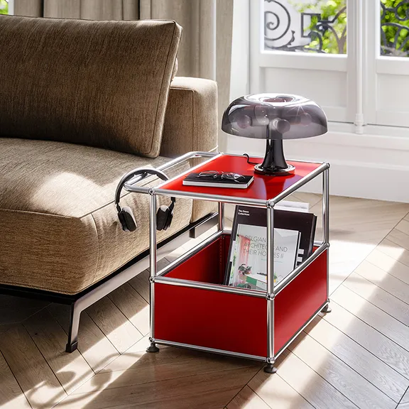 Ein kleiner USM Haller Beistelltisch in Rubinrot. Er dient zur Aufbewahrung von Zeitschriften.